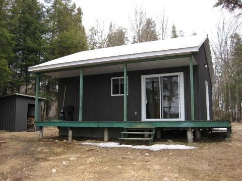 Exterior view of cabin 19 featuring its covered deck and dark siding in the forest.