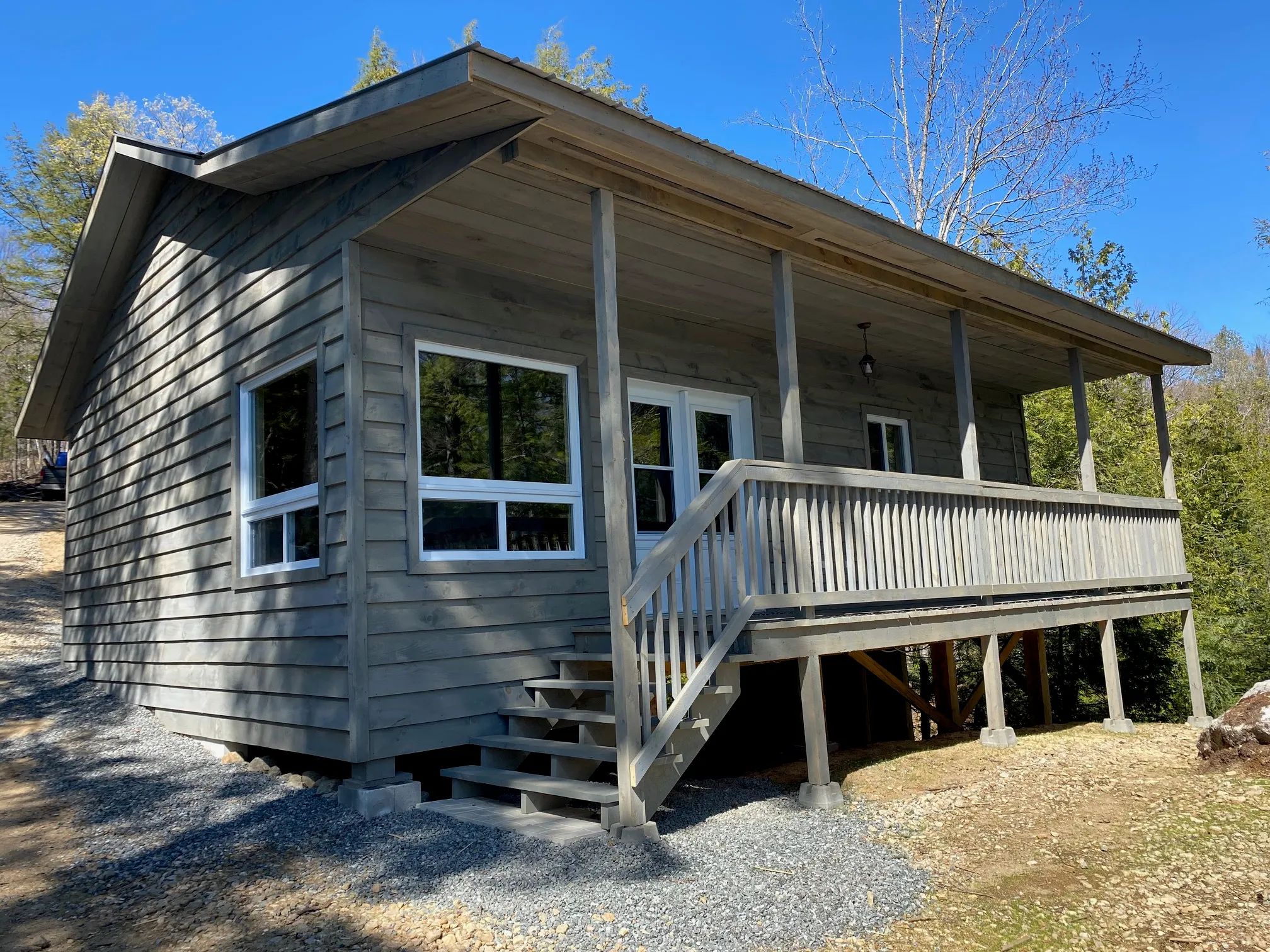 Vue latérale du chalet 19 avec son revêtement en bois et sa galerie couverte.