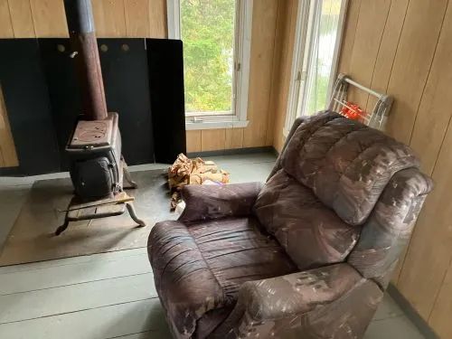 Le salon du chalet comporte un fauteuil confortable près du poêle à bois.