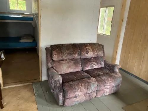 Coin salon avec divan et accès vers la chambre à coucher munie de lits superposés.