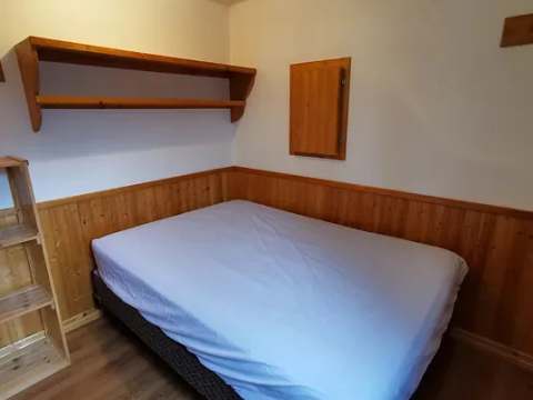 Cette chambre du chalet comprend un lit double avec une tablette de rangement murale.