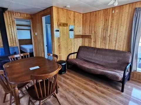 Espace de vie principal du chalet avec table à manger, divan-lit et poêle à bois.