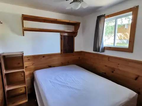 Une chambre confortable avec un lit et des rangements en bois dans le chalet.
