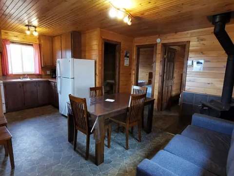 Open concept kitchen, dining area and living room with wood stove in cabin 15.