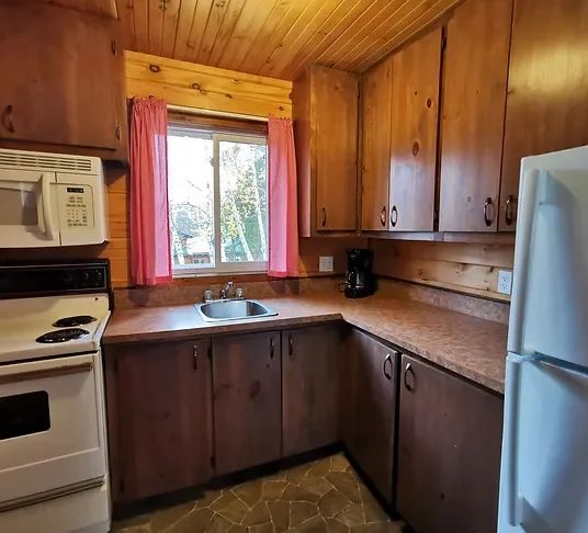 The cottage's functional kitchen features wooden cabinets and full appliances.