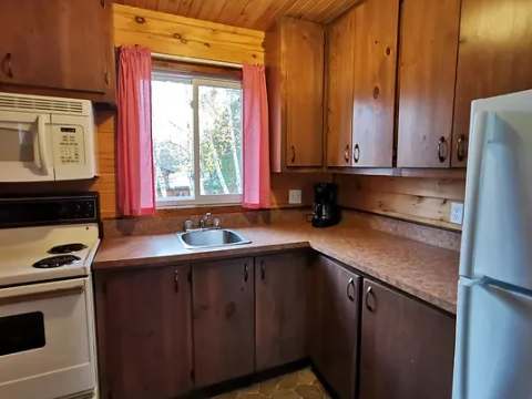 The cottage's functional kitchen features wooden cabinets and full appliances.