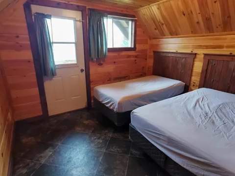 This cabin bedroom features two single beds in a warm wood interior.