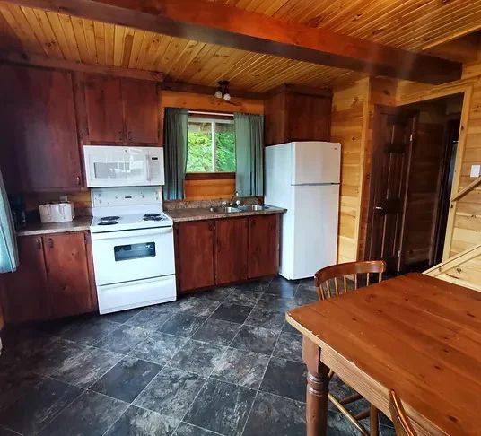 The cottage's functional kitchen includes a stove, a refrigerator, and a dining area.
