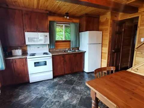The cottage's functional kitchen includes a stove, a refrigerator, and a dining area.