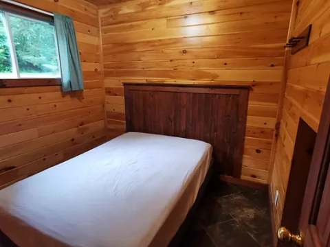 This bedroom features a double bed in a natural wood interior setting.