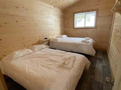 Cette chambre de chalet comprend deux lits doubles avec literie blanche.