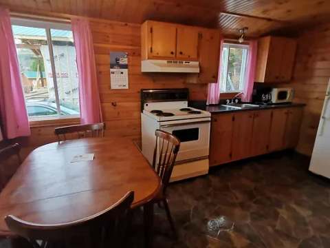 Vue de la cuisine et de la salle à manger du chalet 4 avec ses murs en bois naturel.