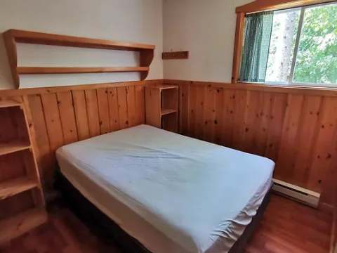 This cozy bedroom features a comfortable bed and natural wood paneling.