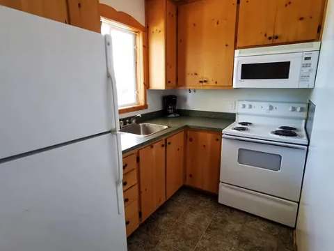 The cabin's equipped kitchen features a refrigerator, a stove, and pine cabinets.