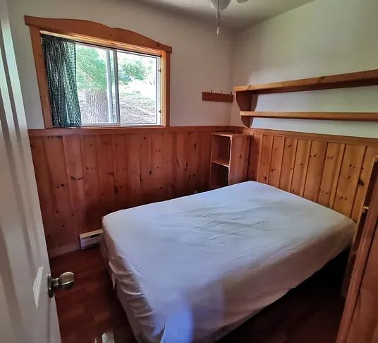 This bedroom features a double bed with wood paneling on the walls.