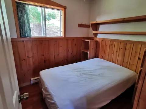 This bedroom features a double bed with wood paneling on the walls.