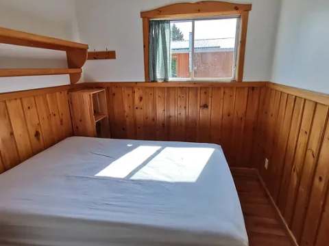 This cottage bedroom features a double bed and wood-paneled walls.