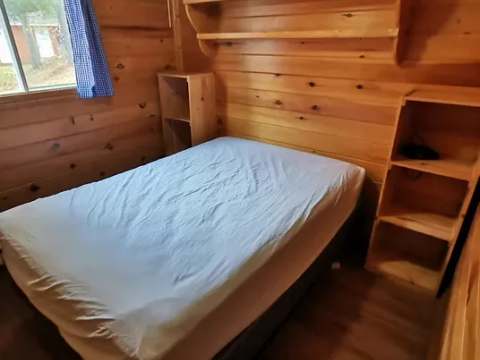 Cette chambre rustique est équipée d'un lit double et de tablettes de rangement en bois.
