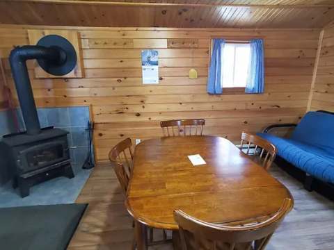 L'espace de vie du chalet comprend une table à manger et un poêle à bois.