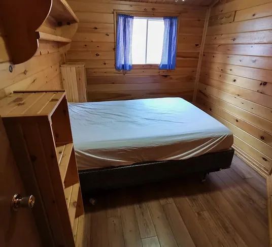 Vue de l'intérieur d'une chambre rustique en bois avec un lit double.