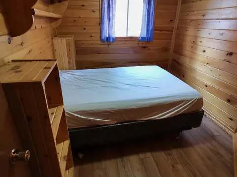 Vue de l'intérieur d'une chambre rustique en bois avec un lit double.