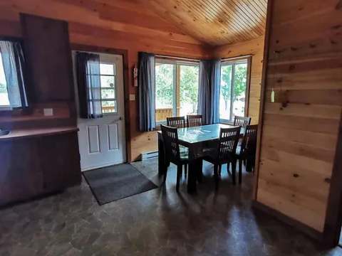 The cottage dining area features a wooden table with a view of the outdoors.