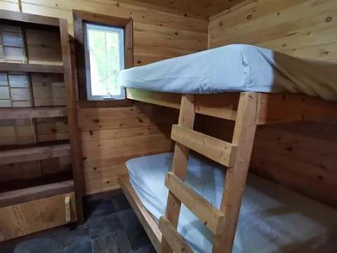A wooden bunk bed is set up in this rustic bedroom of the refuge.
