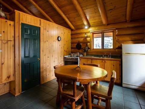 The log cabin kitchen features a dining table and a refrigerator.