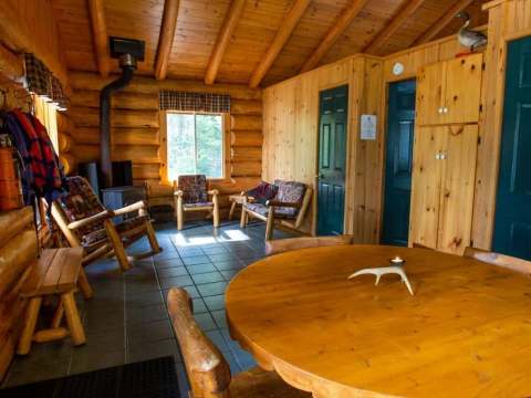 The cottage's dining area and living room feature warm log cabin architecture.