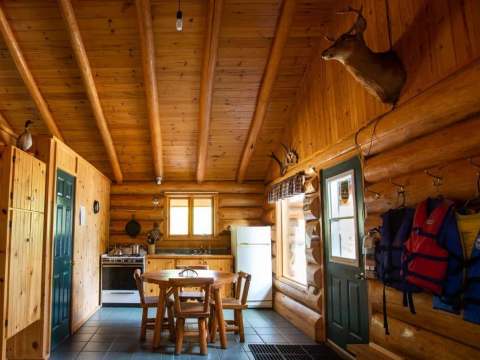 The kitchen and dining area of the Chalet du Barrage featuring log walls.