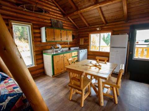 La cuisine rustique et la salle à manger du Chalet du Gardien avec ses murs en bois rond.