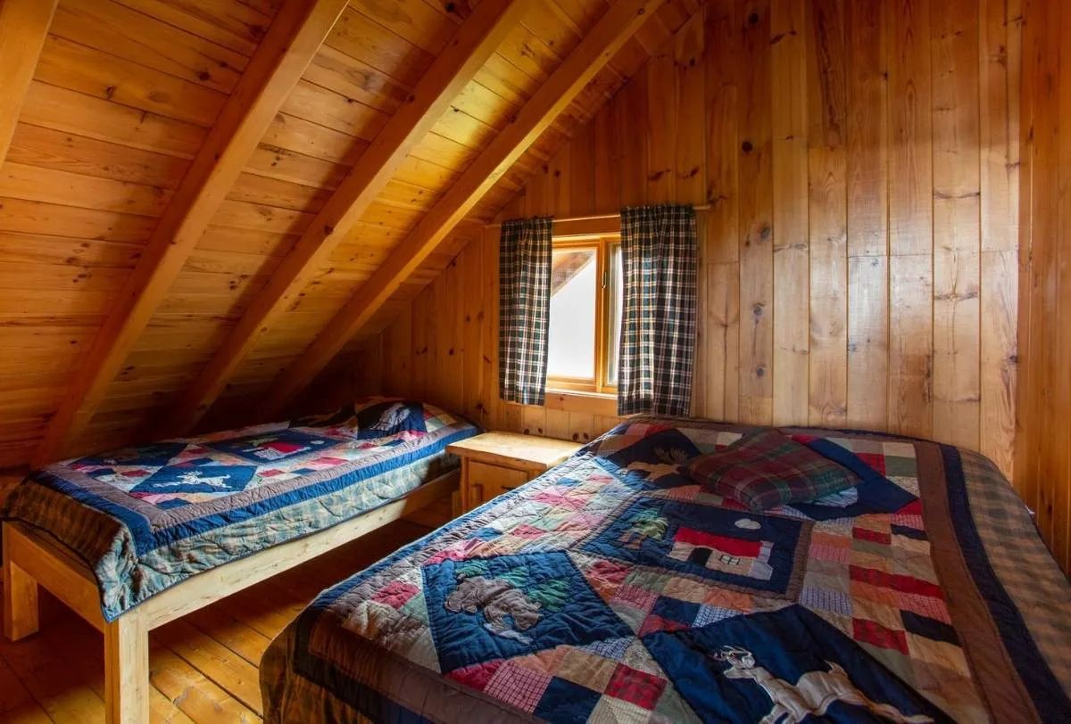 This room under the roof features two beds with rustic quilts.