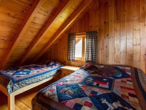This room under the roof features two beds with rustic quilts.