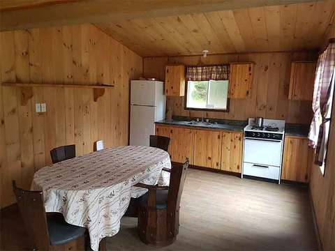 The functional kitchen of the Drapeau chalet includes a dining table and home appliances.