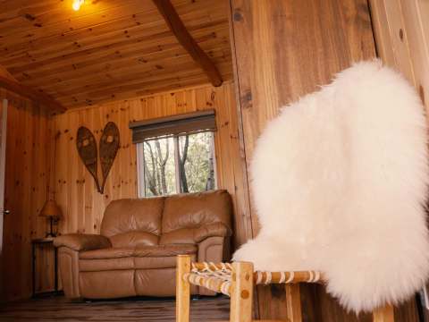 The cozy cottage living room features a leather sofa and wooden decorations.