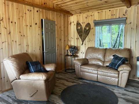 The Chouette Épervière cottage living room is furnished with a comfortable sofa and armchair.