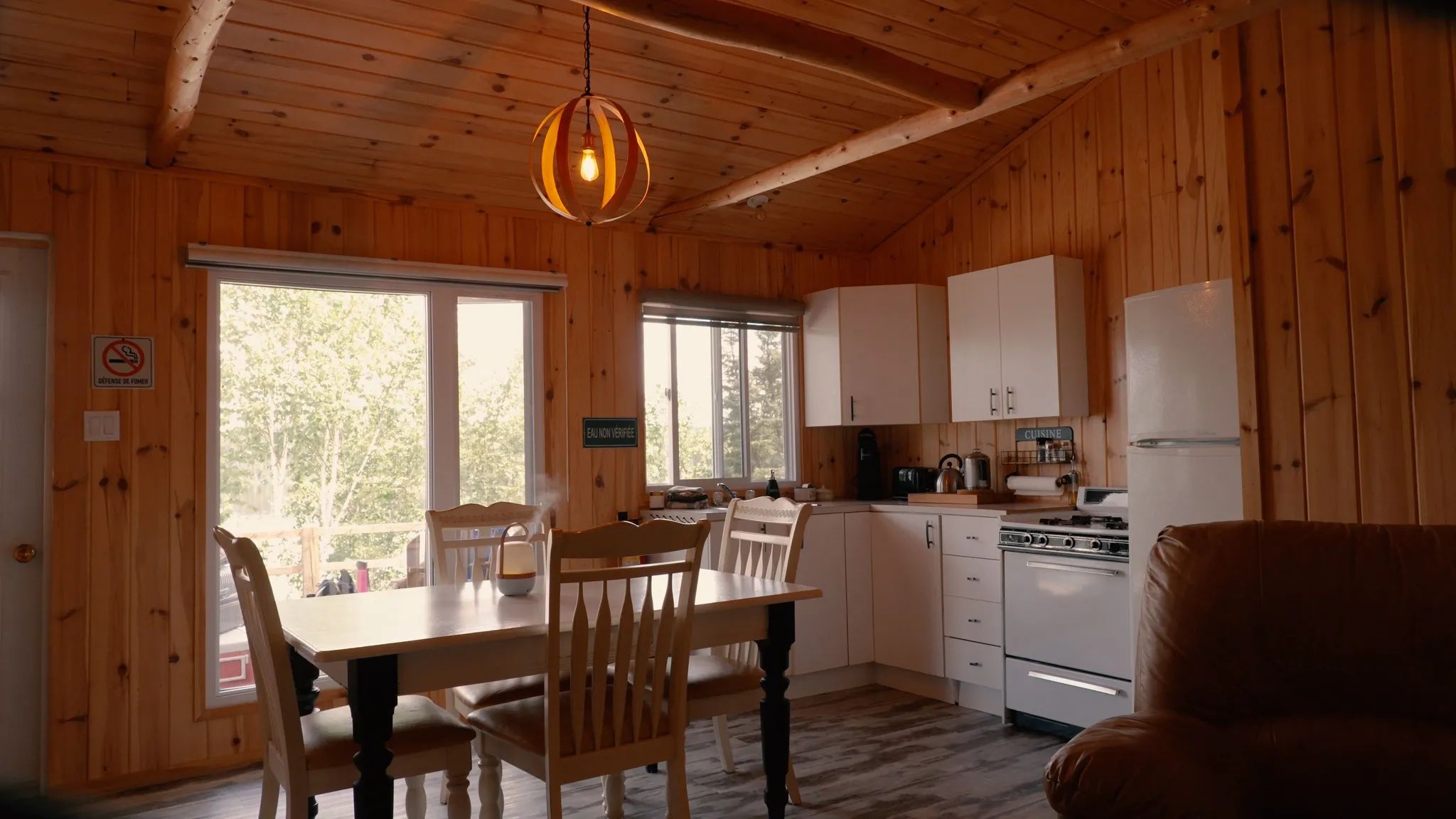 Kitchen and dining area with log walls in the Chouette Épervière chalet.