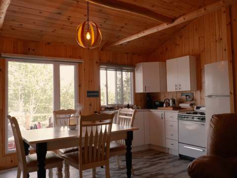 Kitchen and dining area with log walls in the Chouette Épervière chalet.