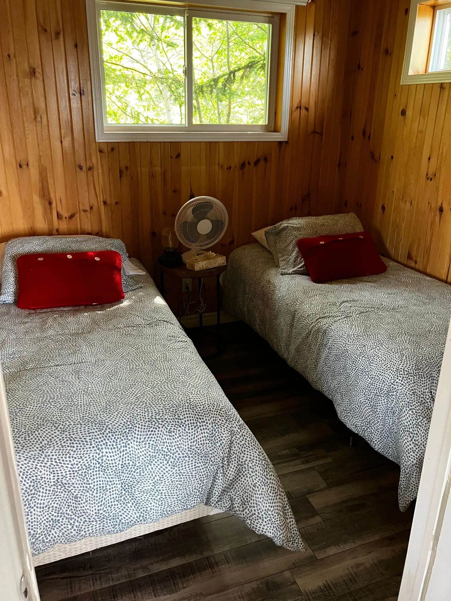 This bedroom in the Grand Duc cottage features two single beds with wood paneling walls.