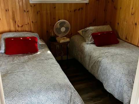 This bedroom in the Grand Duc cottage features two single beds with wood paneling walls.