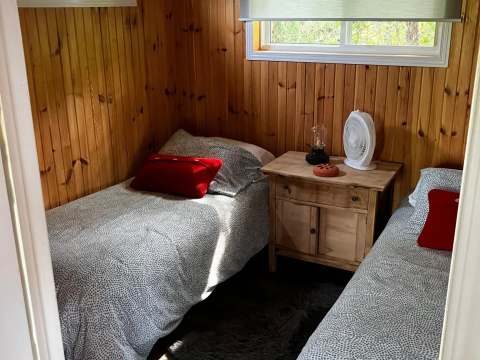 This bedroom features two single beds with a wooden nightstand at the Grand Duc cottage.