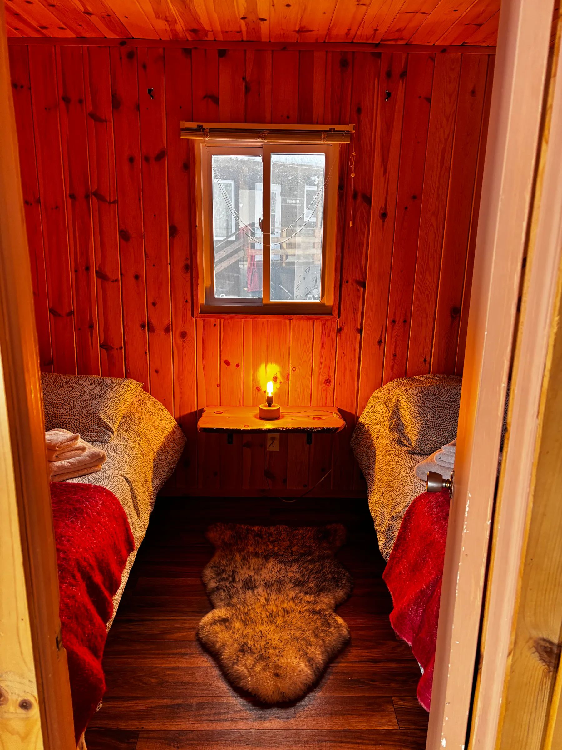 Overhead view of the rustic wooden bedroom in the Petite Nyctale cabin.