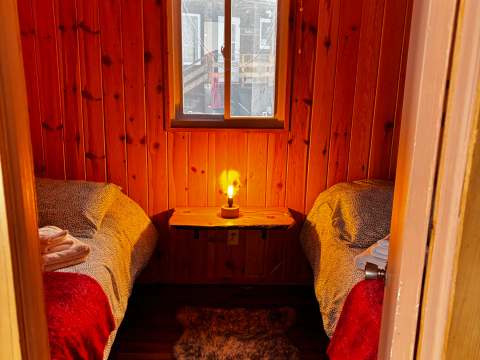 Overhead view of the rustic wooden bedroom in the Petite Nyctale cabin.