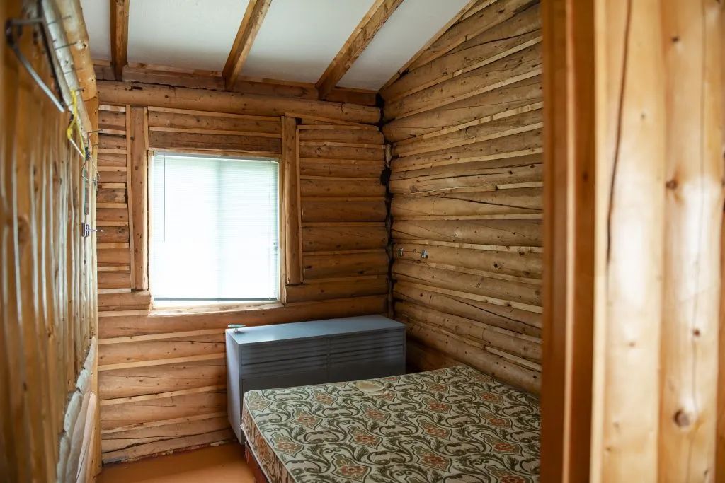 Cette chambre rustique est équipée d'un lit simple et de murs en bois rond.