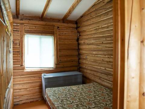 Cette chambre rustique est équipée d'un lit simple et de murs en bois rond.