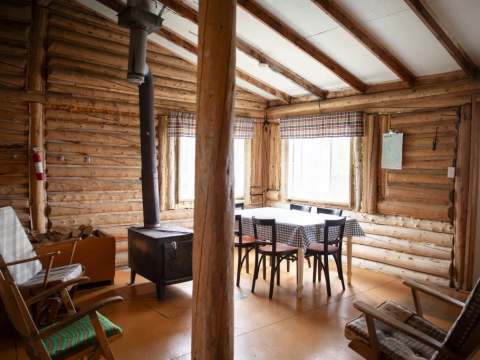 L'aire de vie du chalet comprend une table à manger et un poêle à bois.