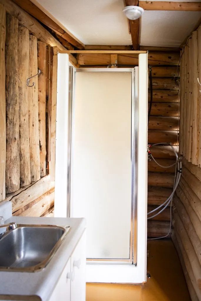 La salle de bain du chalet inclut une douche et un lavabo intégrés dans un décor en bois rond.
