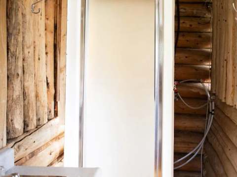 La salle de bain du chalet inclut une douche et un lavabo intégrés dans un décor en bois rond.