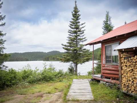 Vue sur le lac depuis la terrasse du chalet en bois rond.