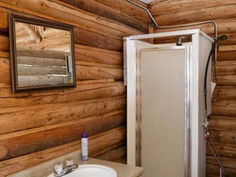 La salle de bain du chalet dispose d'une douche et d'un lavabo intégrés dans un décor en bois rond.